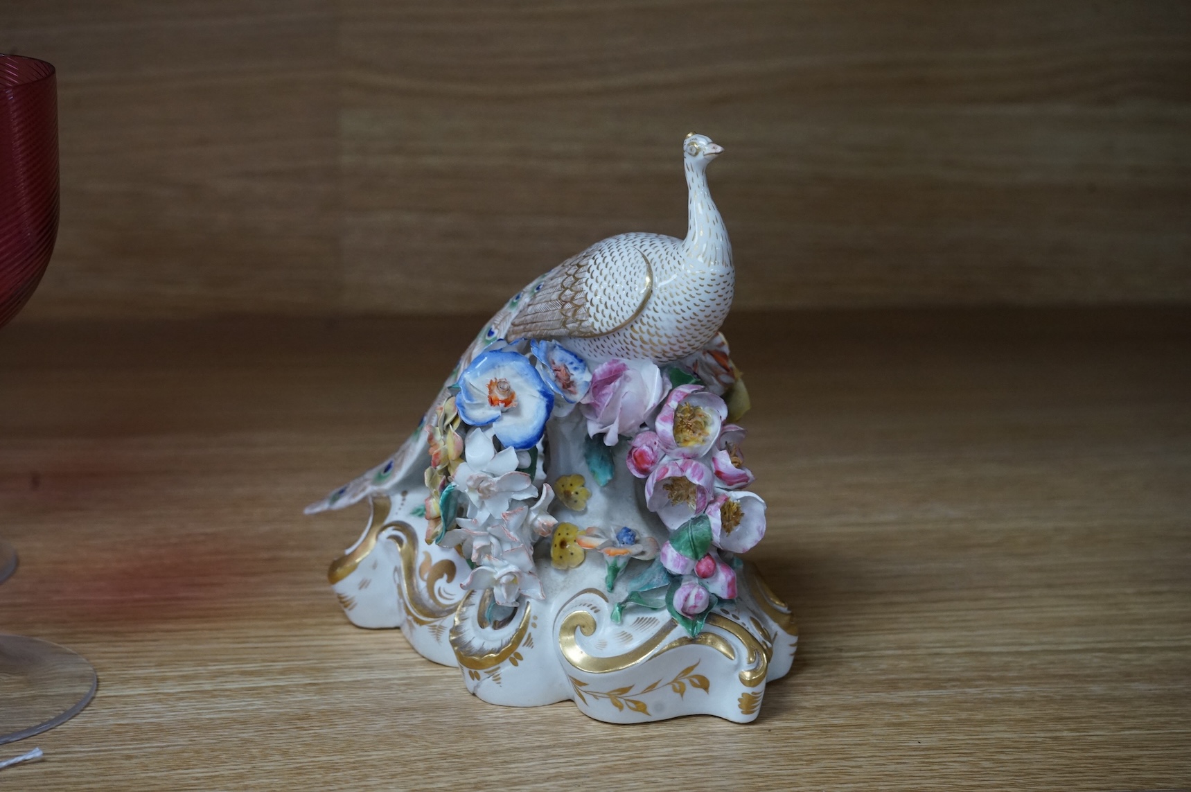 An ornate Bloor Derby peacock with floral encrusted decoration, 16cm high
